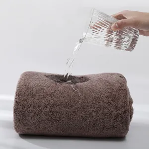 Brown coral fleece wearable bath towel showing high water absorption with a glass pouring water.