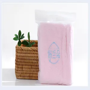 Detail shot of a pink coral fleece hair drying cap inside frosted plastic packaging bag
