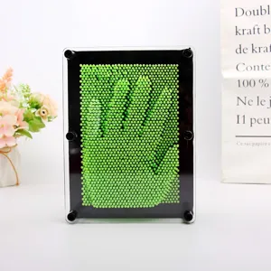 Gros plan d'un jouet 3D Pin Art montrant une empreinte de main en plastique vert.