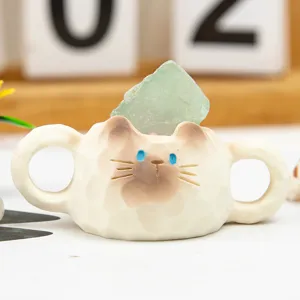Close-up of a handmade cat-shaped resin holder with a green raw fluorite crystal stone.