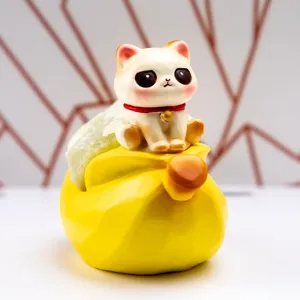 Gros plan d'une figurine de chat en résine avec collier rouge sur un sac de fortune jaune