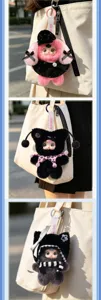 Three cute Yumi plush doll keychains in pink and black on a beige canvas bag.