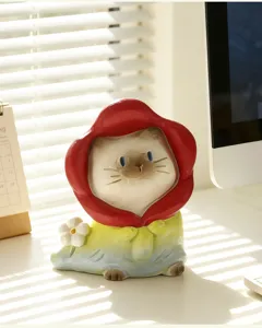 Gros plan d'une adorable figurine de chat blind box portant une capuche rouge et fleur