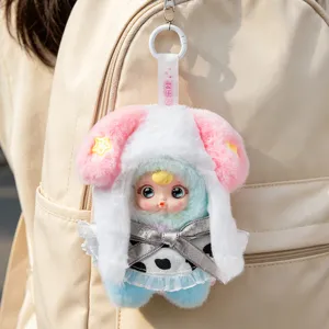 Adorable plush monster keychain featuring a baby face and pink star hood on a beige bag
