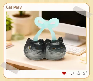Détail macro d'une figurine en résine de chat noir jumeau avec un nœud décoratif bleu