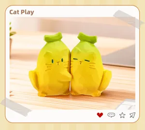 Gros plan de deux adorables figurines de chat en résine en forme de banane sur un bureau en bois.