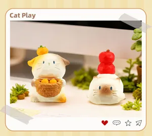 Détail de deux mignonnes figurines de chat en résine avec des fruits dans un cadre.