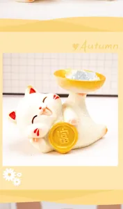 Detailansicht einer niedlichen Maneki Neko Harzfigur mit Glücksmünze und Kristall