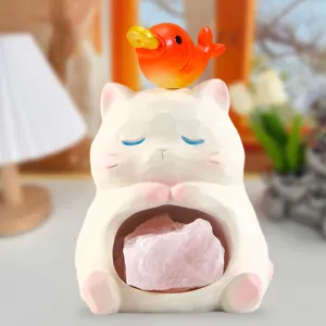 Gros plan d'un mignon chat en résine tenant une pierre de cristal rose naturelle brute