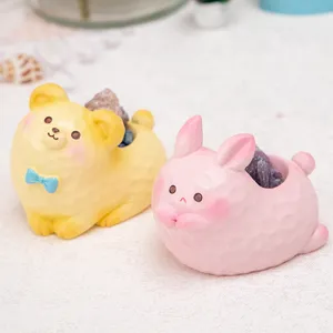 Gros plan de figurines de lapin rose et d'ours jaune en résine avec surface texturée.