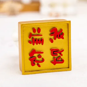 Detailed view of a golden resin desk ornament featuring red embossed Chinese script