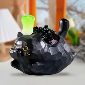 Vue détaillée d'une figurine de chat noir à facettes avec un accent de chou vert.