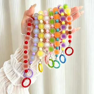 Hand holding multiple colorful frosted jelly beaded phone charms with carabiner clips.