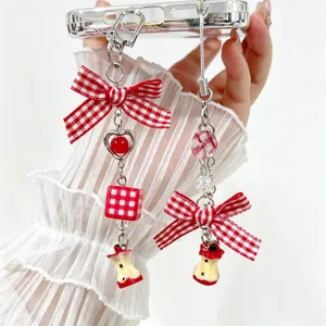 A detailed close-up view of a cute apple core phone charm with a red checkered bow