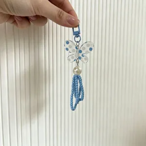 Close-up of a blue beaded butterfly phone charm with a pearl and blue polka dots