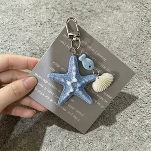 Détail d'un porte-clés thème océan avec étoile de mer bleue, coquillage et pendentifs poisson