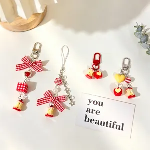 Close-up of cute apple core charms and keychains with red checkered bows and hearts.