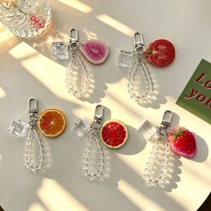 Colorful fruit keychains with crystal beads and ice cube charms on a sunny table
