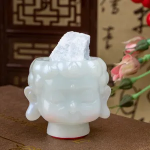 Close-up of white resin Buddha head figurine with decorative crystal stone detail on top