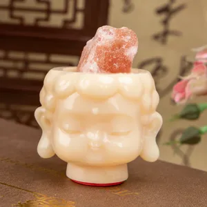 Macro view of a Zen Buddha head resin figurine featuring pink Himalayan salt rock