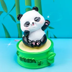Close-up of a cute resin panda figurine sitting on a green bamboo-themed display base
