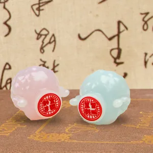 Close-up of pink and blue resin sheep figurines with cultural blessing stickers