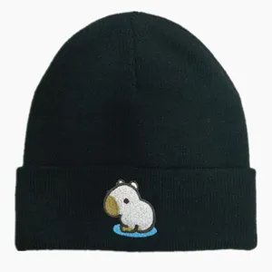 Détail d'un bonnet en tricot noir avec un dessin animé de capybara brodé mignon.