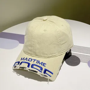 Detailansicht der beigen Distressed-Baseballkappe mit blauer Stickerei und ausgefranster Krempe.