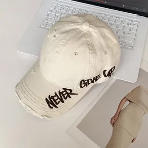 Primer plano de una gorra de béisbol de algodón desgastado beige con bordado detallado.