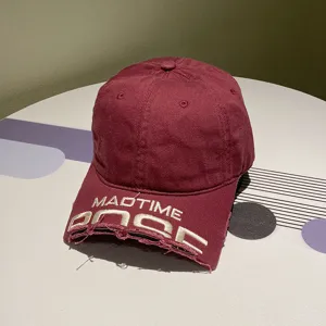Nahaufnahme der weinroten Baseballkappe mit MADTIME-Stickerei und zerfleddertem Schirm