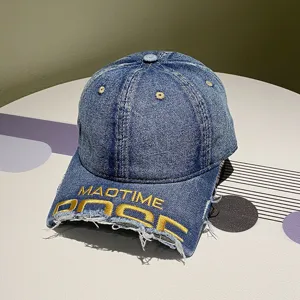 Detail eines Jeans-Basecaps mit gelber Stickerei und ausgefranster Krempe