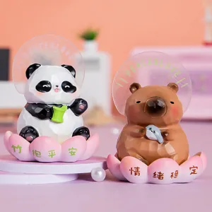 Gros plan de figurines de panda et de capybara assises sur des bases de lotus roses