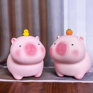 Primer plano de dos huchas de carpincho rosa con adornos de patito y naranja en la cabeza