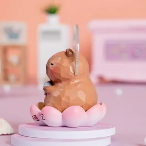 Vue latérale d'une figurine de capybara marron sur un socle en forme de lotus rose