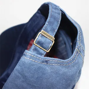 Detailaufnahme der verstellbaren Bronzeschnalle an einer blauen gewaschenen Jeansmütze