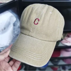 Nahaufnahme einer gewaschenen khakifarbenen Baseballkappe mit rotem Stickbuchstaben C