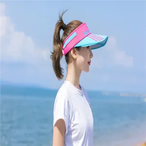 Asiatin trägt einen stylischen rosa-blauen Sport-Sonnenvisierhut an einem Strand