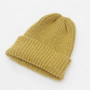 Primer plano de un gorro de punto acanalado amarillo mostaza sobre fondo blanco liso