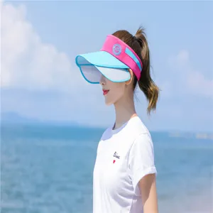 Seitenansicht einer Frau mit rosa-blauem Sonnenvisier am sonnigen Strandhintergrund