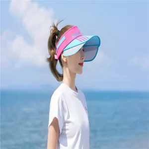 Asiatische Frau mit pink-blauem Sonnenschutzvisier mit breiter Krempe am Strand