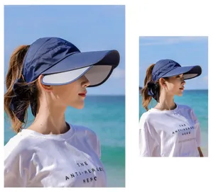 Asiatin trägt einen marineblauen Sonnenhut mit breiter Krempe am sonnigen Strand
