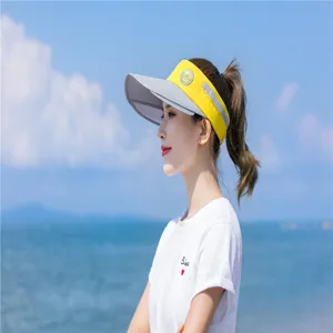 Seitenansicht einer Frau mit gelbem und grauem Sonnenvisier am sonnigen Strand