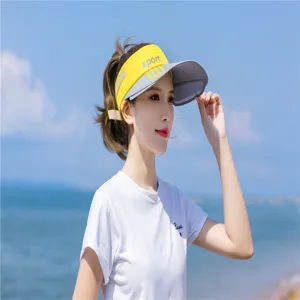 Asiatische Frau trägt ein gelbes Sport Sonnenvisier am Strand zum Sonnenschutz