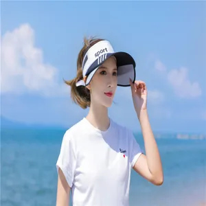 Junge Frau am sonnigen Strand mit weißem Sport-Sonnenvisier für Sonnenschutz