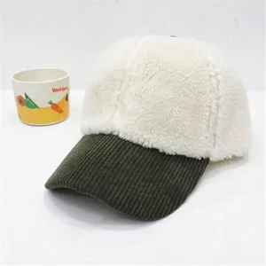 Detail of white sherpa baseball cap with a dark green corduroy brim for winter warmth.