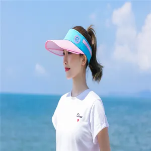 Seitenansicht einer Asiatin mit pink-blauem Sonnenvisier am sonnigen Strand zum Sonnenschutz