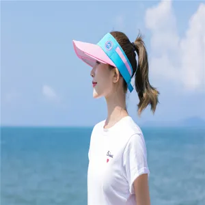 Seitenansicht einer Frau mit einem rosa-blauen Sonnenvisier am sonnigen Strandhintergrund
