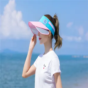 Seitenansicht einer Frau mit rosa-blauem Sonnenvisier-Hut am sonnigen Strand