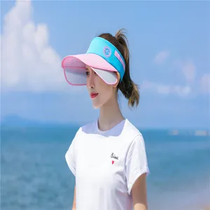 Asiatische Frau trägt ein rosa-blaues Sonnenvisier an einem sonnigen tropischen Strand