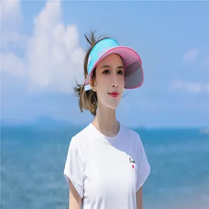 Asiatisches Model trägt eine blau-pinke Sonnenblende am sonnigen Sommerstrand